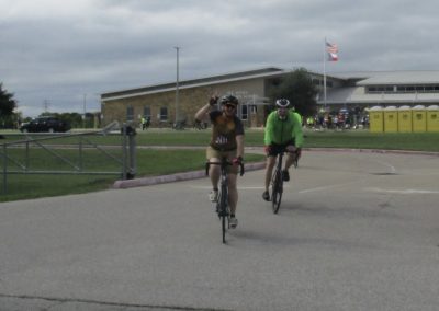Bright cyclist riding with a victory sign during Bluebonnet Express bike race event.