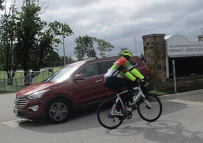 Cyclist riding past a car near Herman T. Jones Elementary School in Texas.