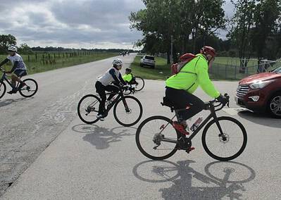 Kids cycling on an open road with support from parents during Bluebonnet Express event.