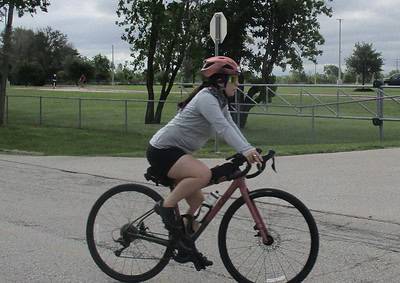 Vibrant pink bicycle at Bluebonnet Express with rider in helmet and sunglasses cycling outdoors.