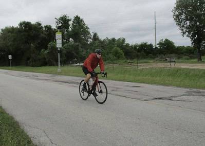 Vibrant cyclist riding on a paved road close to nature, showcasing Bluebonnet Express bike tours.