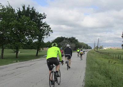 Cyclists riding on a scenic rural road in the Bluebonnet country, enjoying outdoor bike adventure.