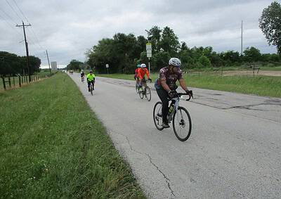 Group of cyclists riding on a rural road, promoting outdoor biking and healthy lifestyle.