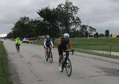 Cyclists riding on a scenic bike path during daytime in Texas, promoting Bluebonnet Express cycling event.