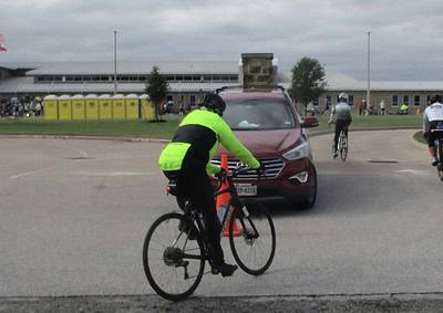 Cyclist in neon jacket avoiding a car on a city street.