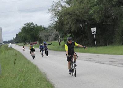 Cyclists riding on a scenic rural road during Bluebonnet Express event in Texas.