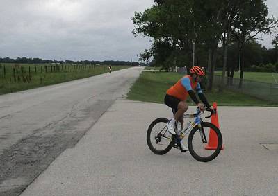 Bright cyclist navigating road safety cones during a daytime bike ride on a scenic trail.