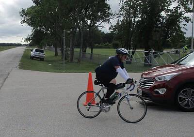 Vibrant parkway scene featuring a cyclist riding past a parked car on a cloudy day.
