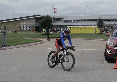 Cyclist riding bike at Bluebonnet Express event outside H.J. Jones Elementary School during daytime.