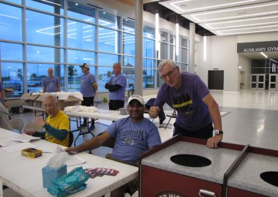 Vibrant indoor scene of Bluebonnet Express volunteers at a community event, smiling and engaging with attendees.