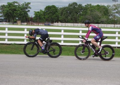 Cyclists riding electric bikes on a paved road during daytime outdoor activity.