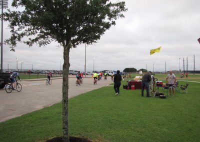 Bright bluebonnet-themed bike event with cyclists and community members enjoying outdoor riding and socializing.
