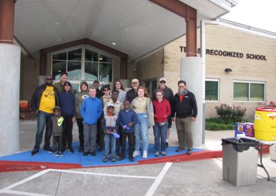 Children and adults gather outside a school, promoting community engagement and safe transportation with Bluebonnet Express.