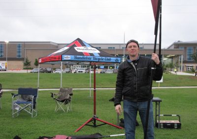 Handlebar Bicycle Club event setup with a person holding a flag at Bluebonnet Express festival.