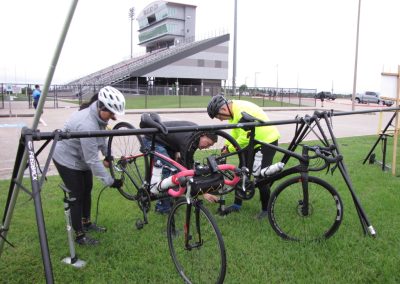 High-performance bicycle repair station at Bluebonnet Express cycling event, with riders servicing bikes before race.