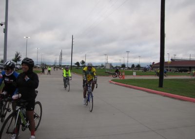 Velo cyclists riding on a community bike path under cloudy skies.