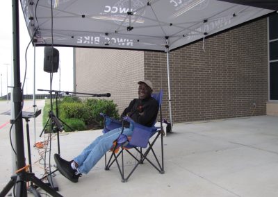 Relaxed man enjoying Bluebonnet Express bike event under tent in outdoor setting.