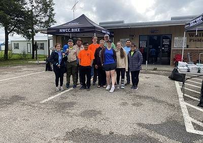 People gathered outside a community center for Bluebonnet Express bike event, showcasing local cycling and outdoor activity.