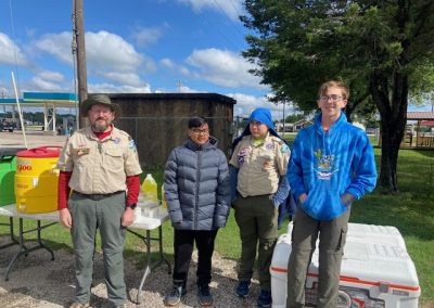 Scout leaders and kids at outdoor event with BBX Bike Bluebonnet Express uniforms and equipment, community engagement.