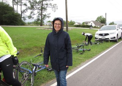 Cyclists taking a break on Bluebonnet Express trail on a rainy day with bikes and supporting vehicles.