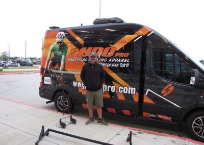 Bike delivery van with sports apparel branding, transportation, and professional cycling logo.