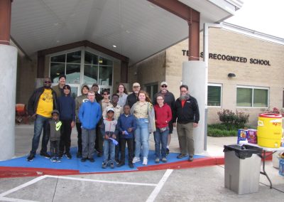 Happy group of kids and adults outside recognized school after Bluebonnet Express bike event.