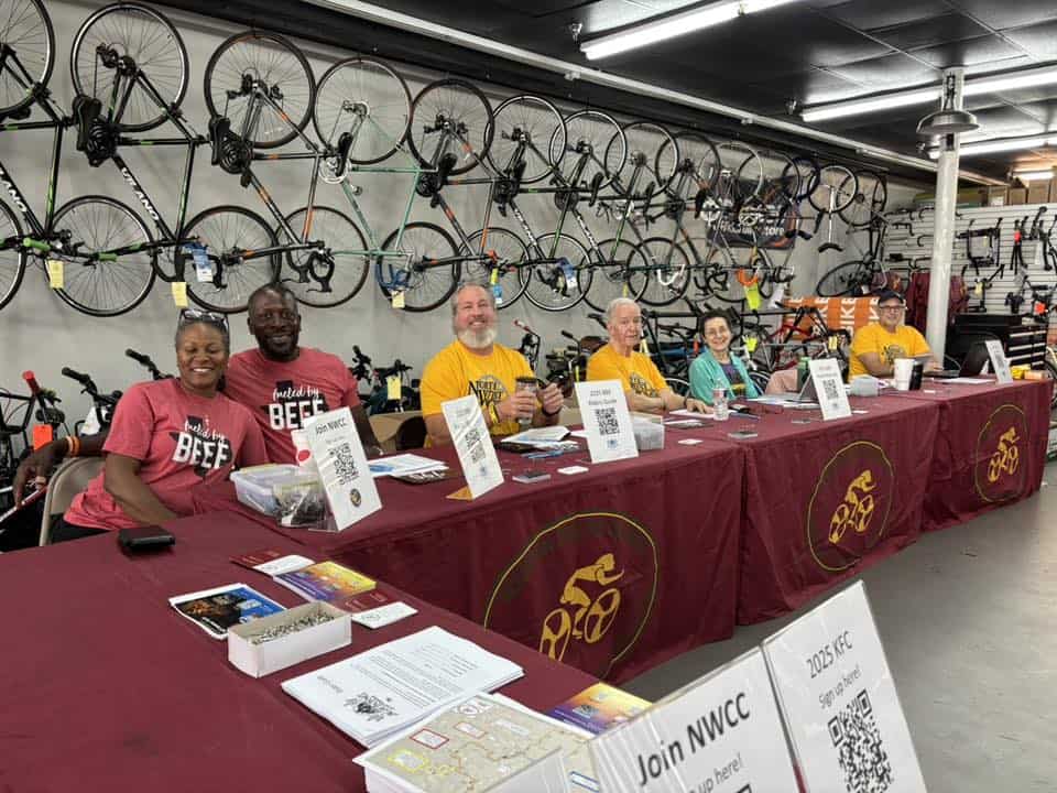 Vivid indoor scene showcasing Bluebonnet Express bicycle event registration table with staff and display bikes.