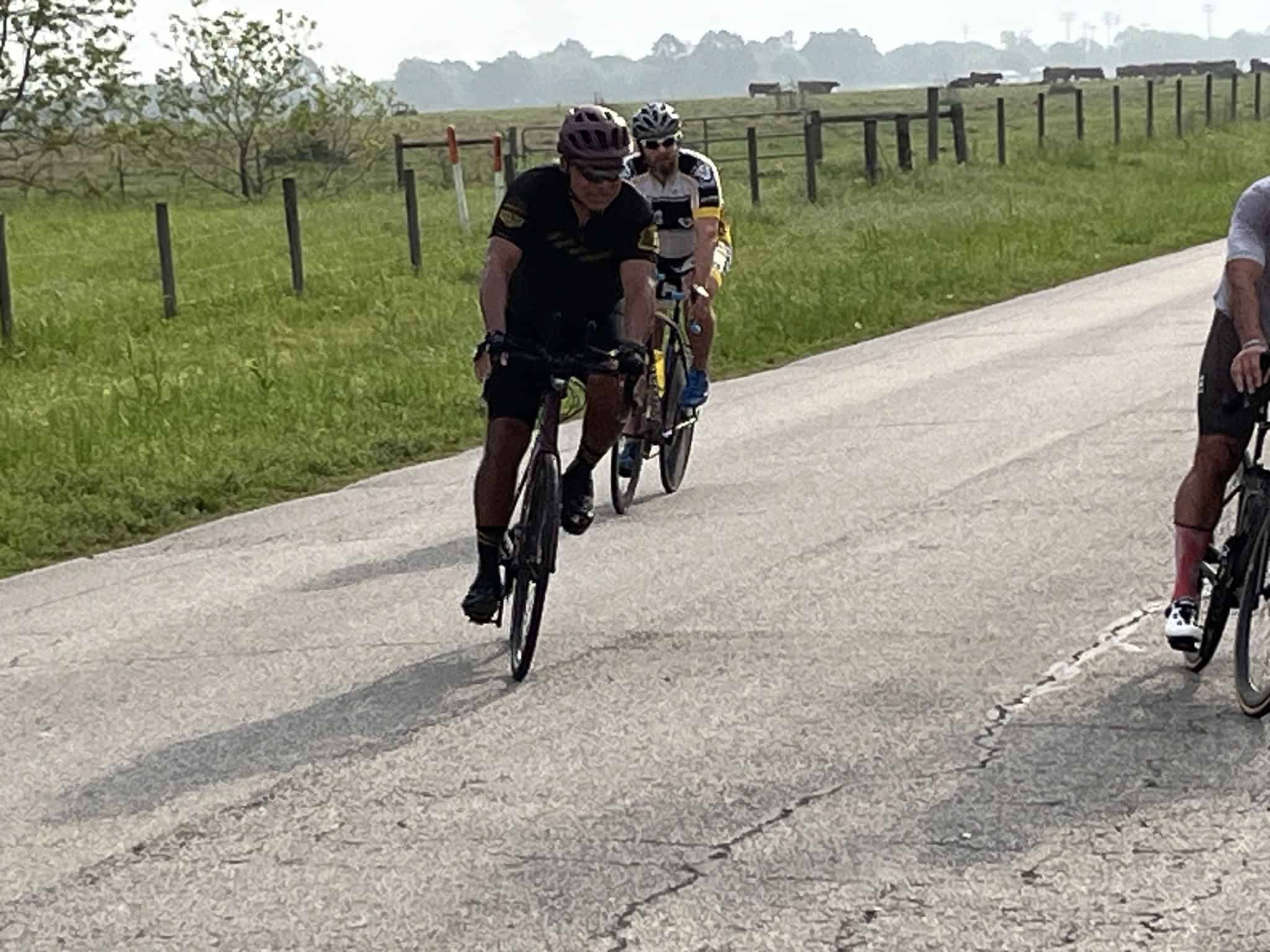 Cyclists riding on a scenic rural road during daytime.