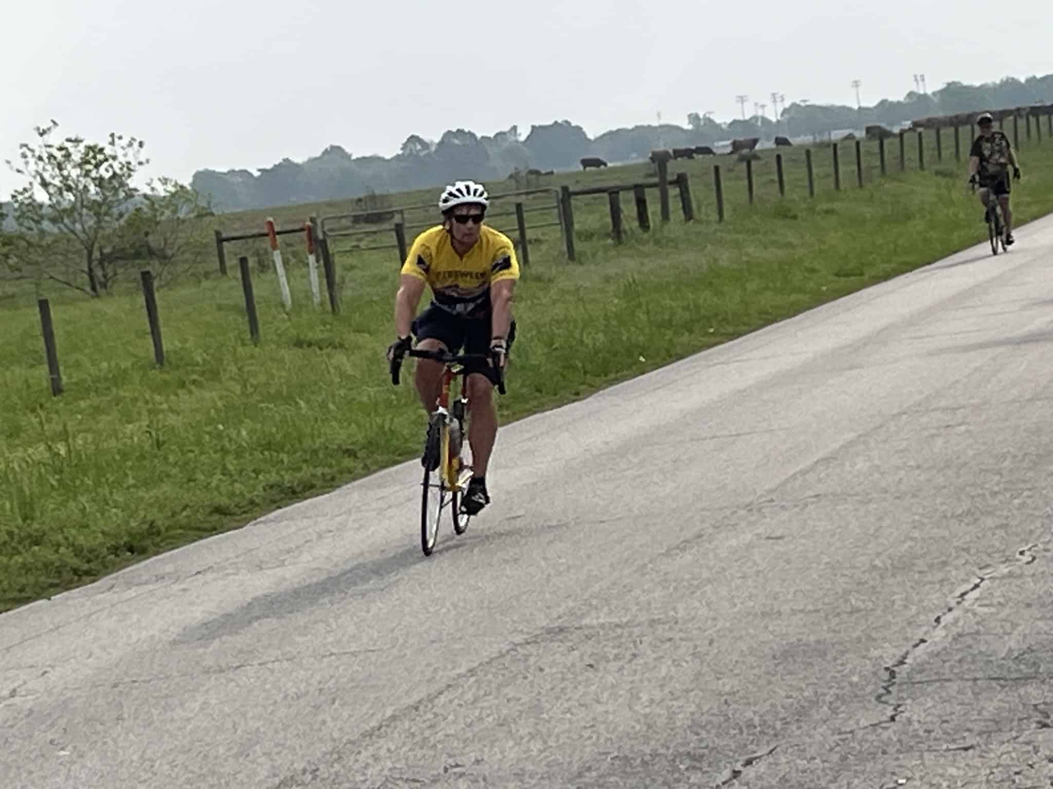 Active cyclist riding on a rural road with scenic countryside background.