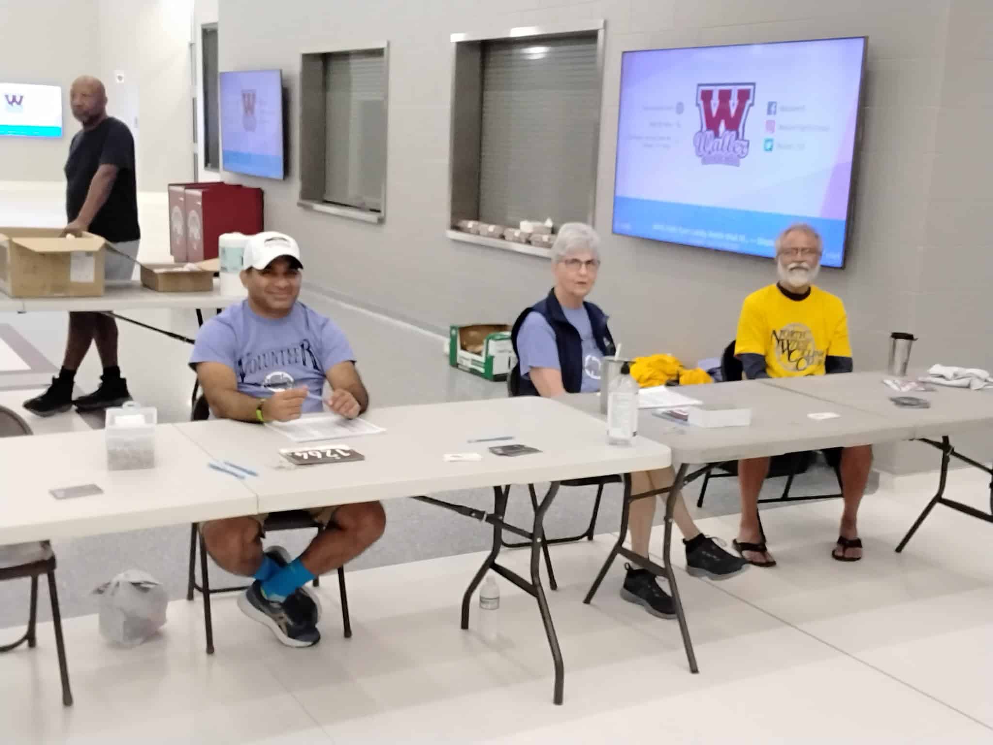 Volunteers at Bluebonnet Express event seated at registration tables in a conference room.