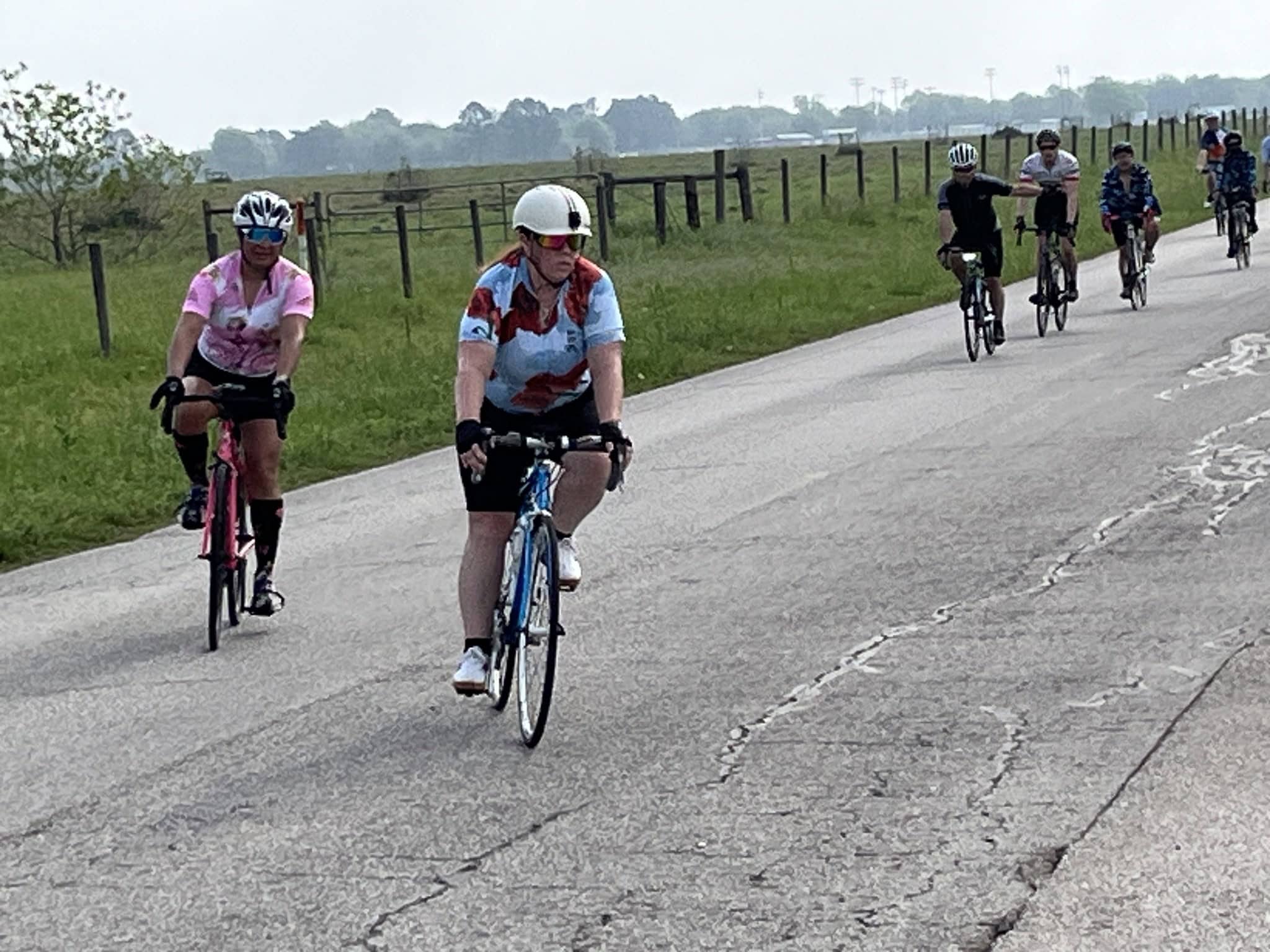 Brightly colored cyclists riding on a rural road, enjoying the scenic Bluebonnet Express ride.