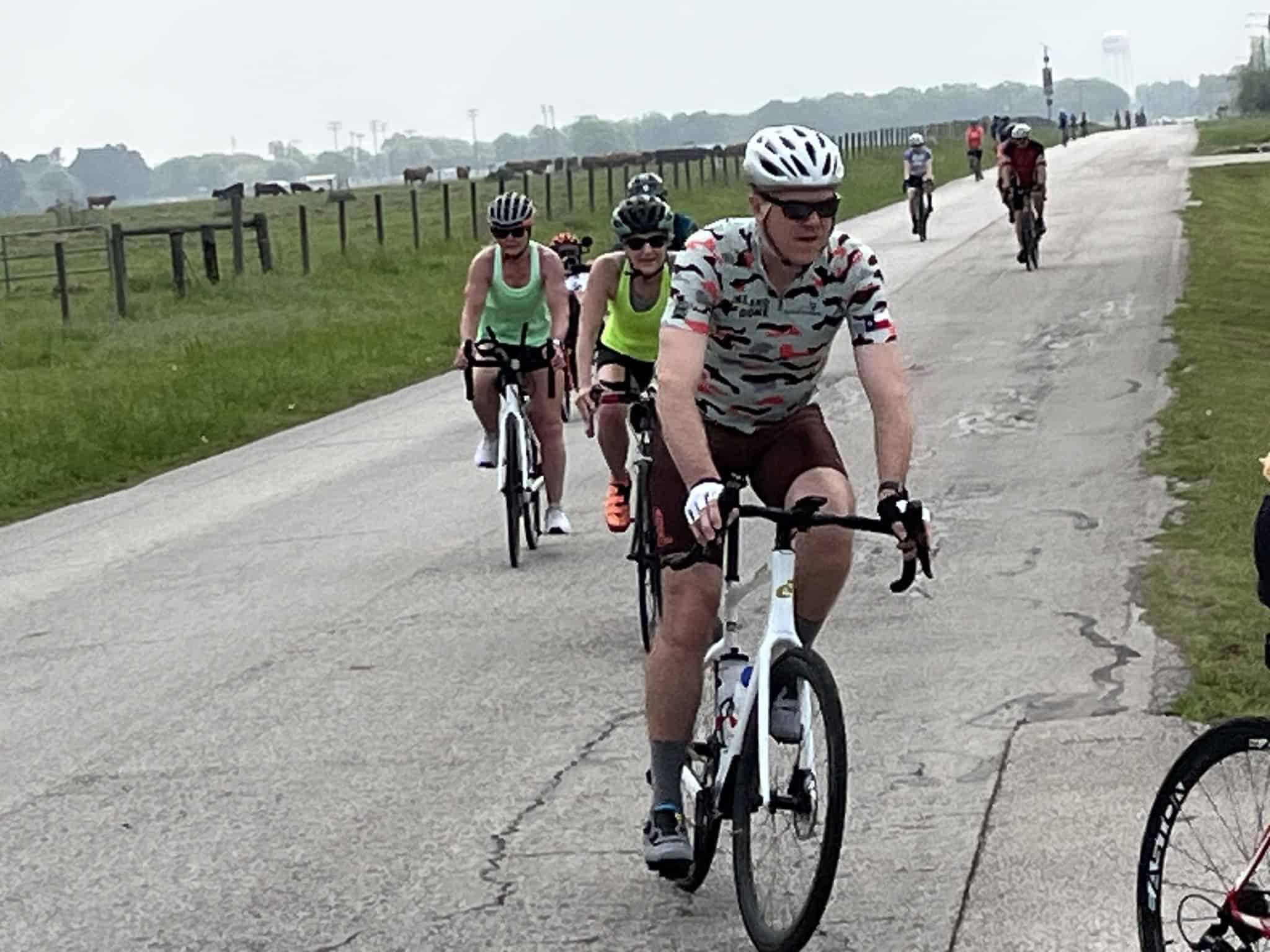 Brightly dressed cyclists riding on a scenic bike trail in Texas, promoting Bluebonnet Express cycling event and outdoor recreation.