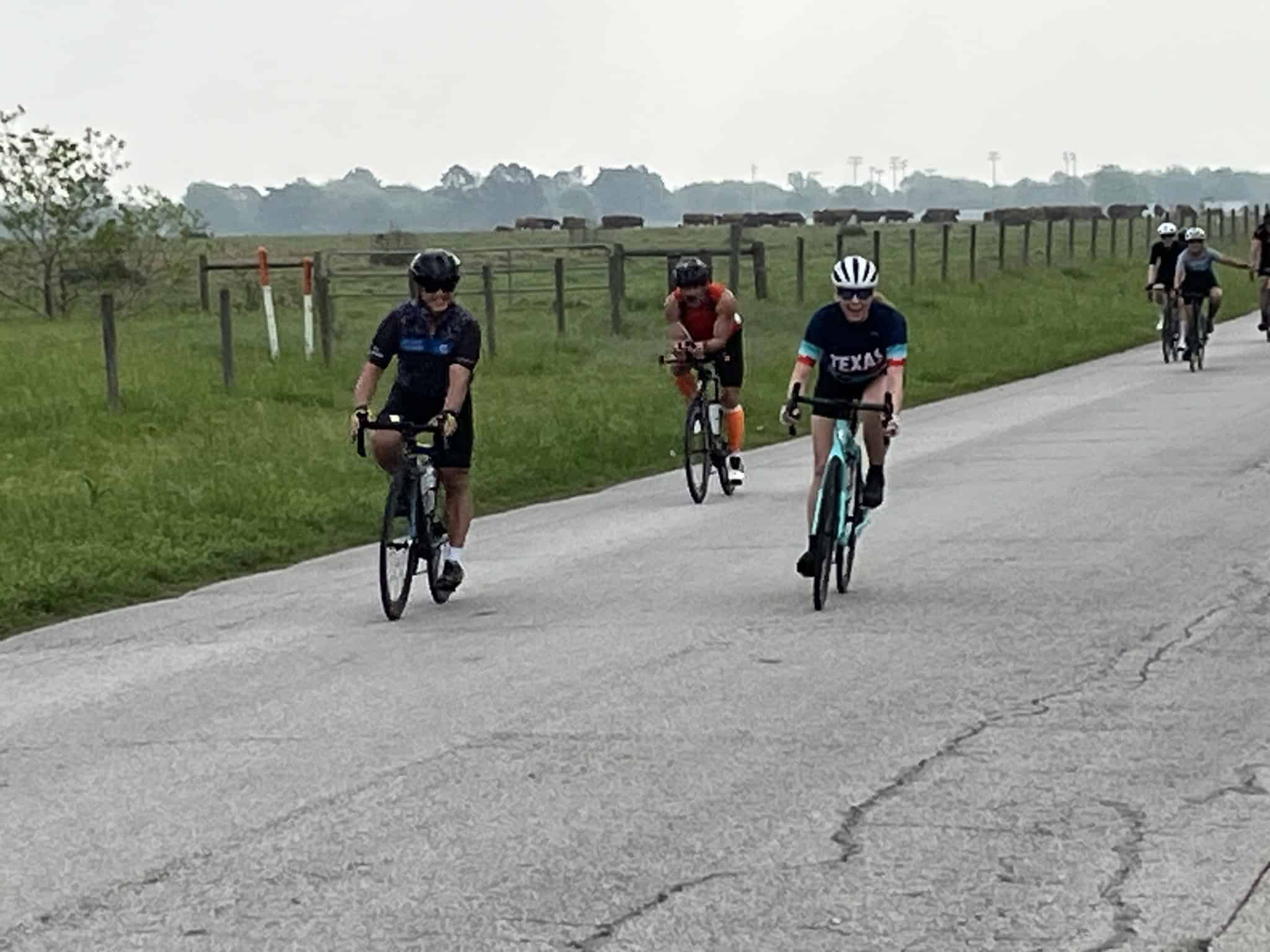 Kids riding bikes on rural road with green fields and cattle in Texas.