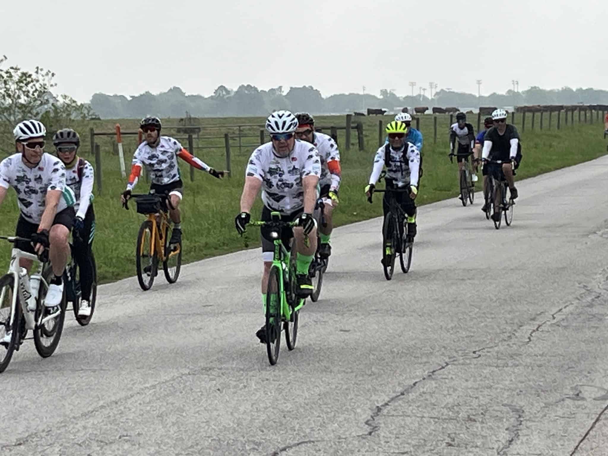 Colorful group of cyclists riding on a country road, promoting Bluebonnet Express biking event.