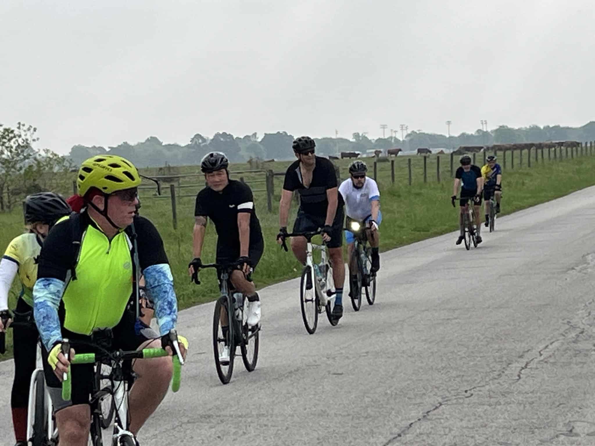 Vibrant cyclists riding on scenic rural road during daytime, promoting Bluebonnet Express bike event.