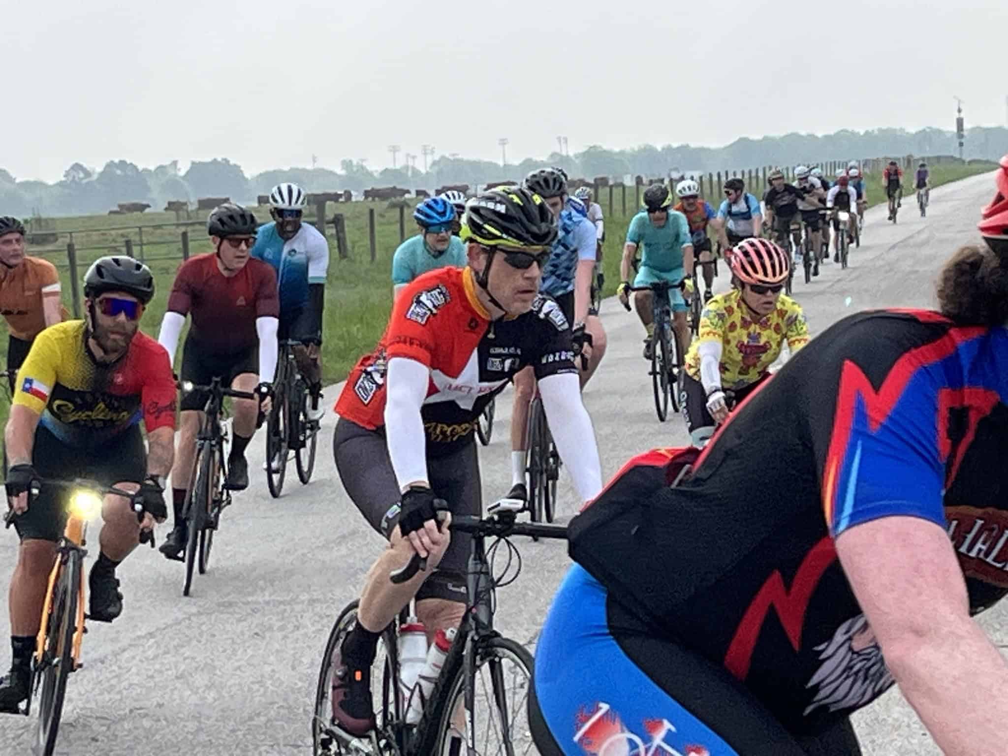 Vibrant group of cyclists riding through scenic countryside on Bluebonnet Express event route.
