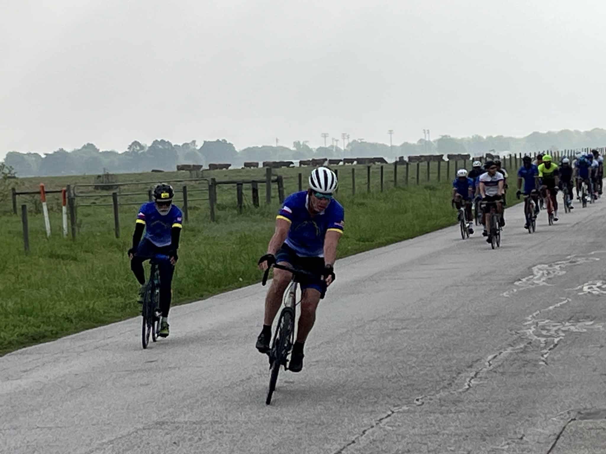 Riders participating in a group bike ride on rural roads during daytime.