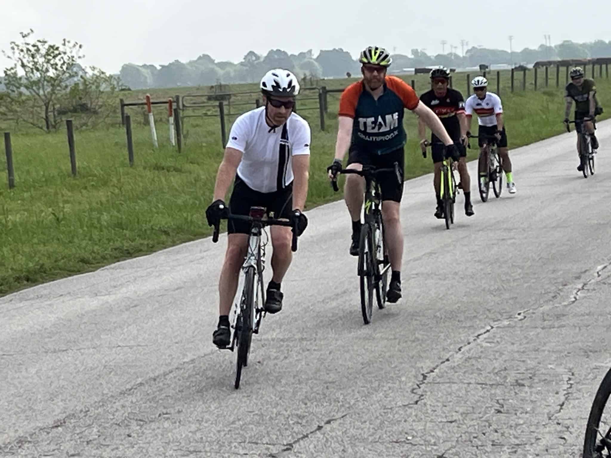 Brightly colored cyclists riding on a rural road during daytime, part of Bluebonnet Express bike event.