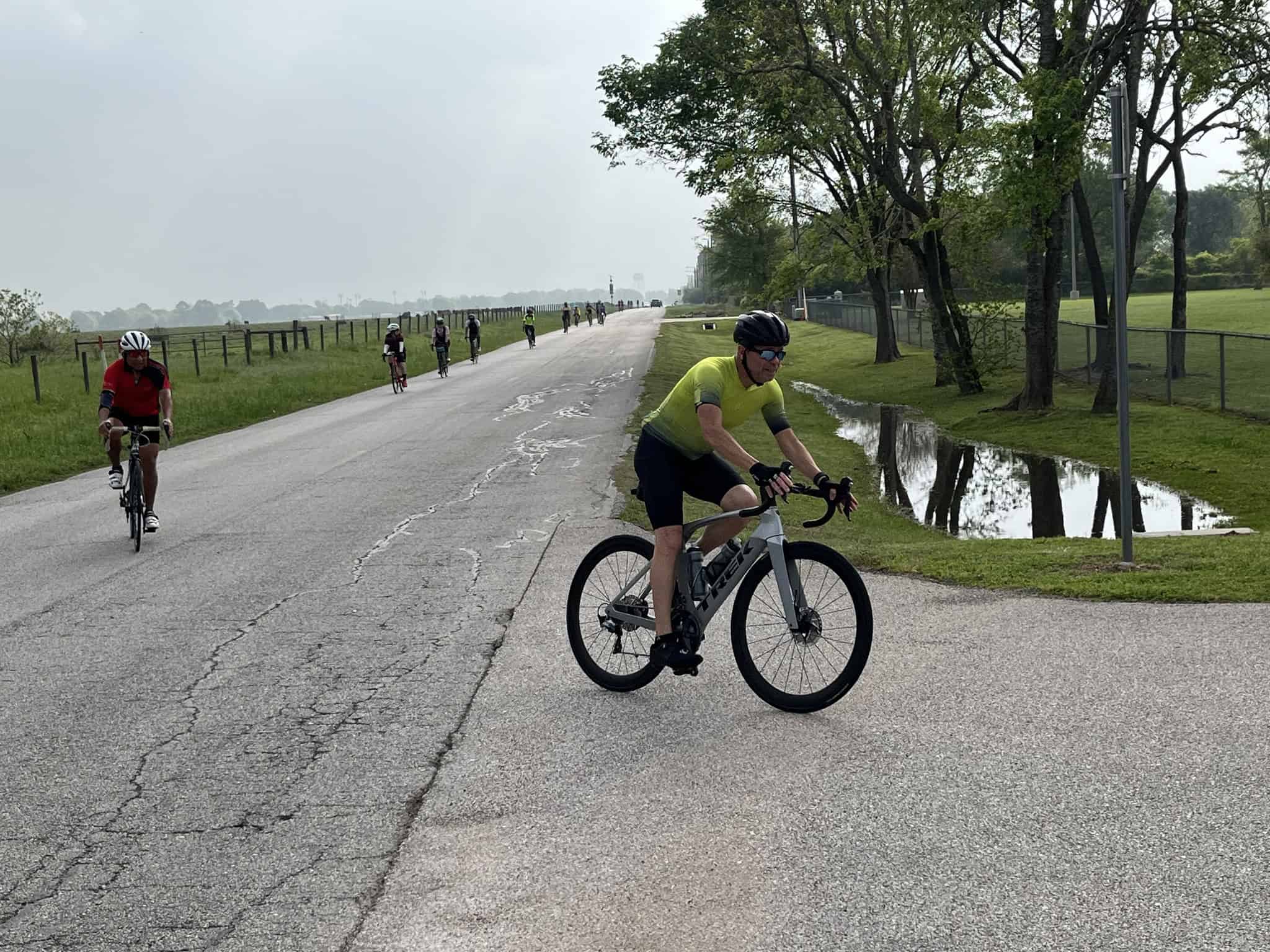 Cyclists riding along a scenic park trail on an overcast day.