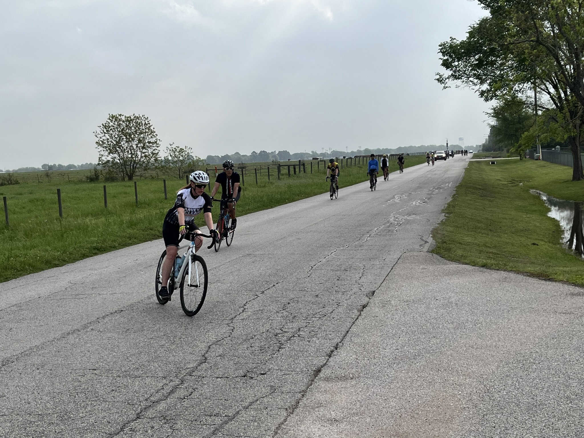 Cyclists riding along a scenic country road during daytime, promoting outdoor biking and cycling tours.