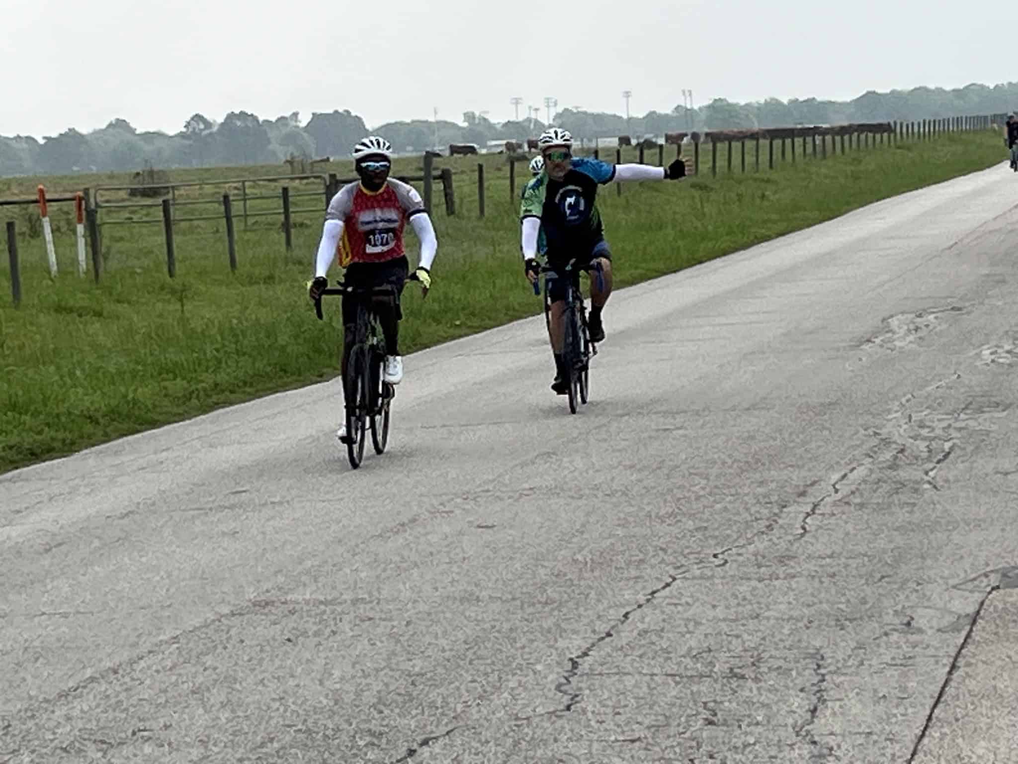Brightly dressed cyclists riding on a rural road in a cycling event, promoting Bluebonnet Express bike tours.