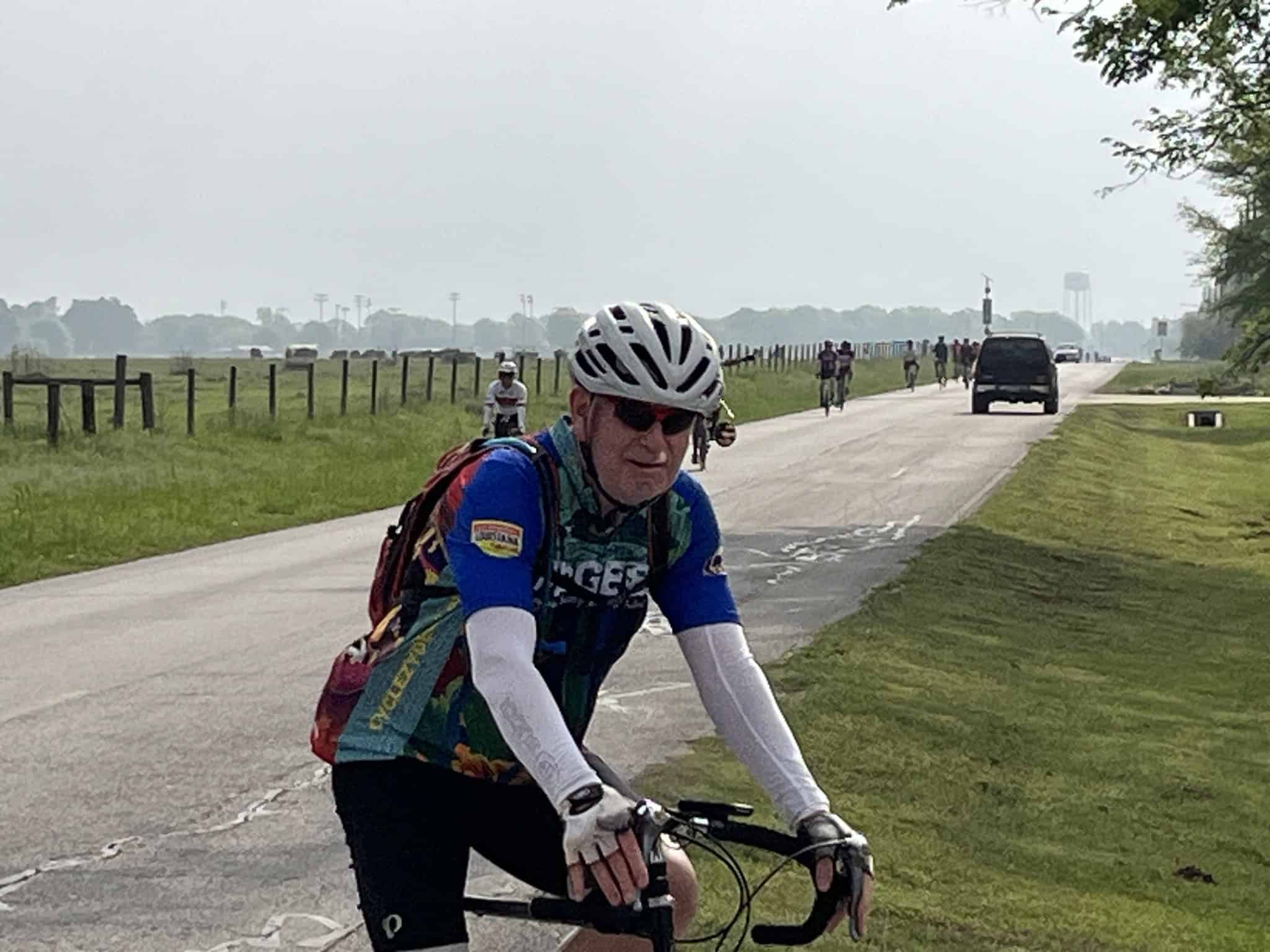 Vegan cyclist riding on a scenic trail with a grassy landscape and clear sky.