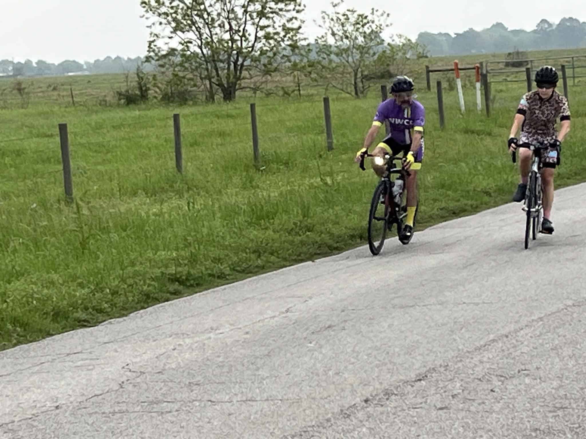 Brightly colored cyclists riding on a scenic rural bike path during daytime, promoting outdoor recreation and cycling adventures.