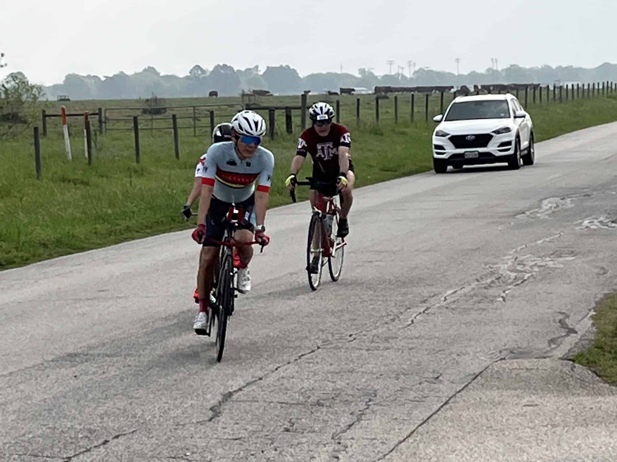 Cyclists riding on a rural road with a support vehicle nearby, showcasing Bluebonnet Express cycling event.