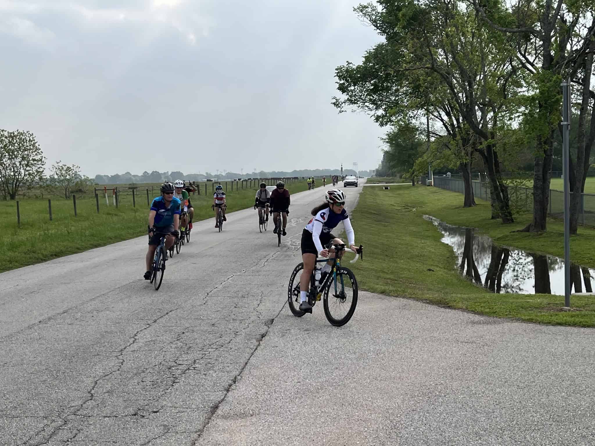 Cyclists enjoying a scenic ride along the Bluebonnet Express trail on a cloudy day.
