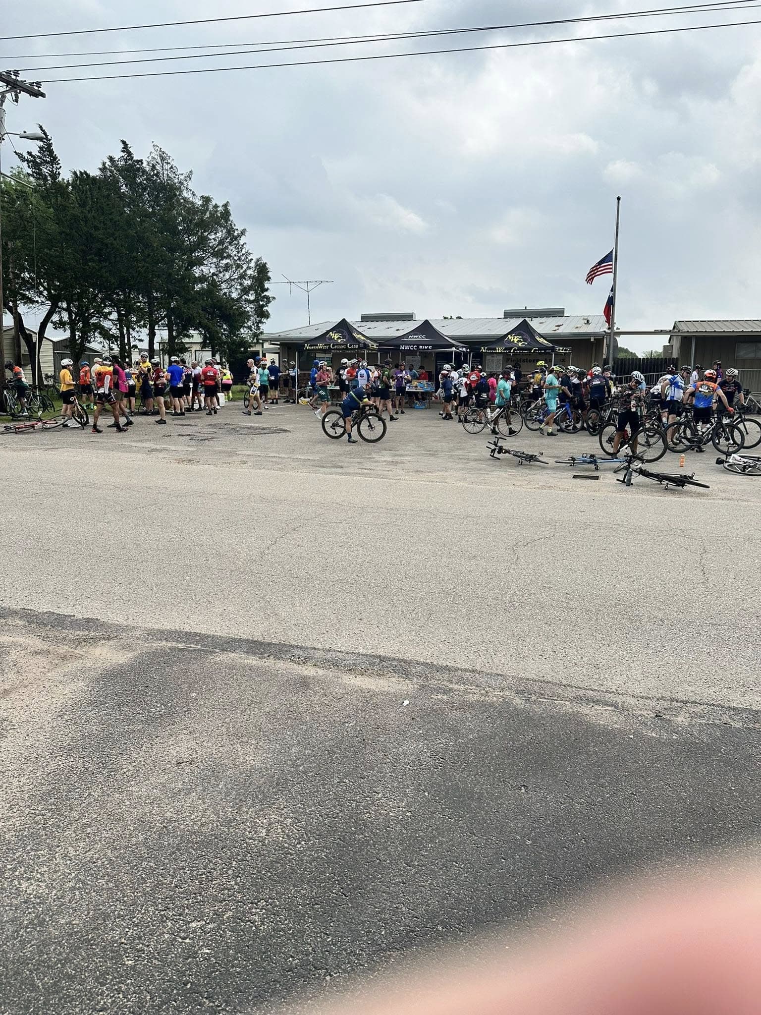 Crowd of cyclists and event tents at Bluebonnet Express bike race registration outdoor station.