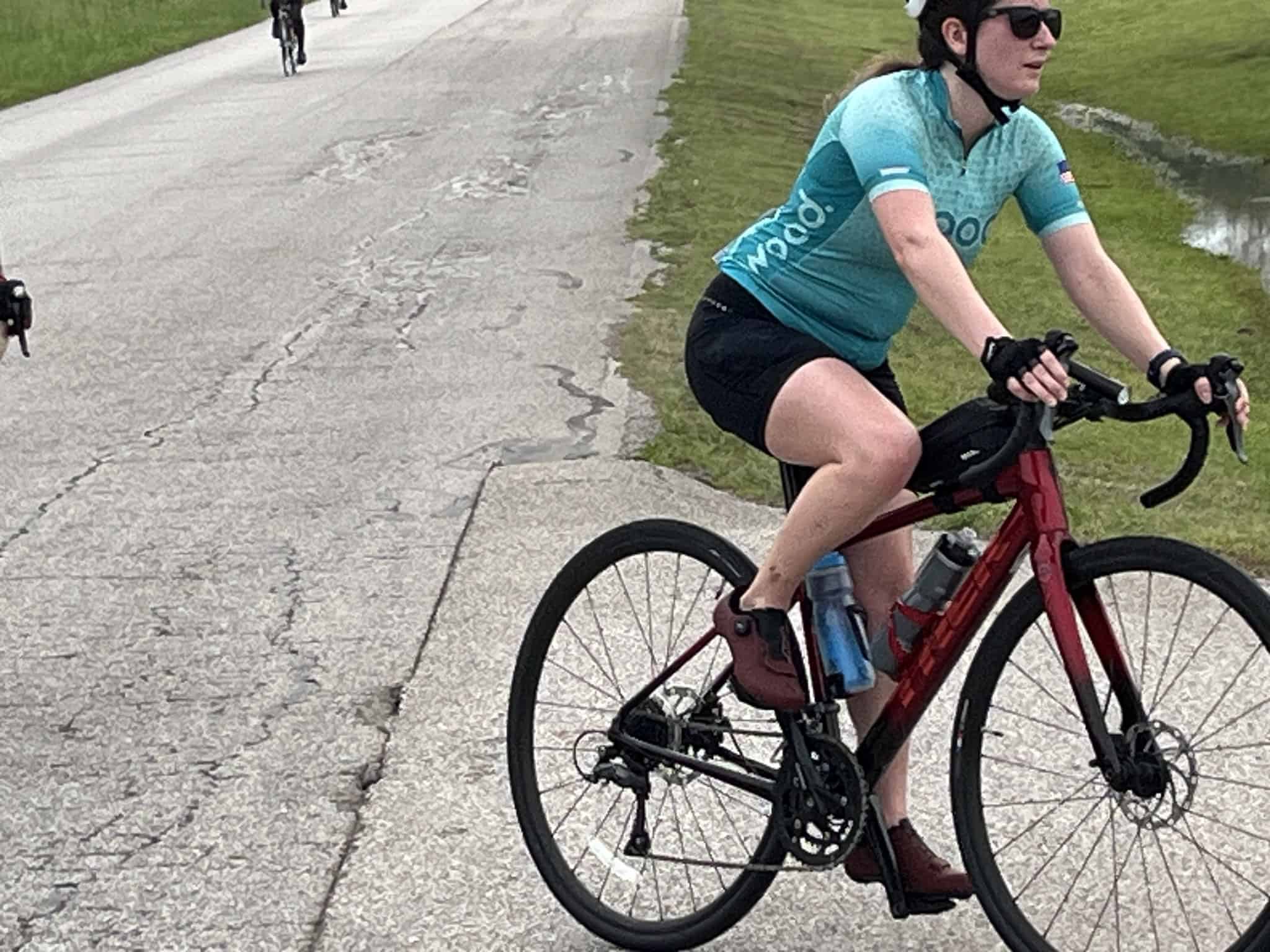 Vegan cyclist riding a red e-bike on a scenic park trail during daytime.