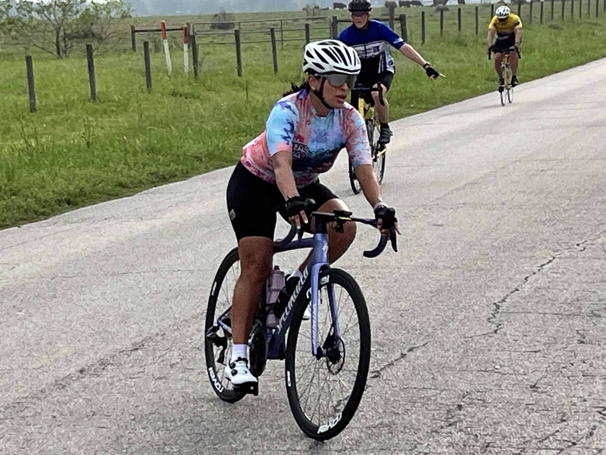 Vibrant cyclist wearing a colorful jersey riding a bike on a rural road.