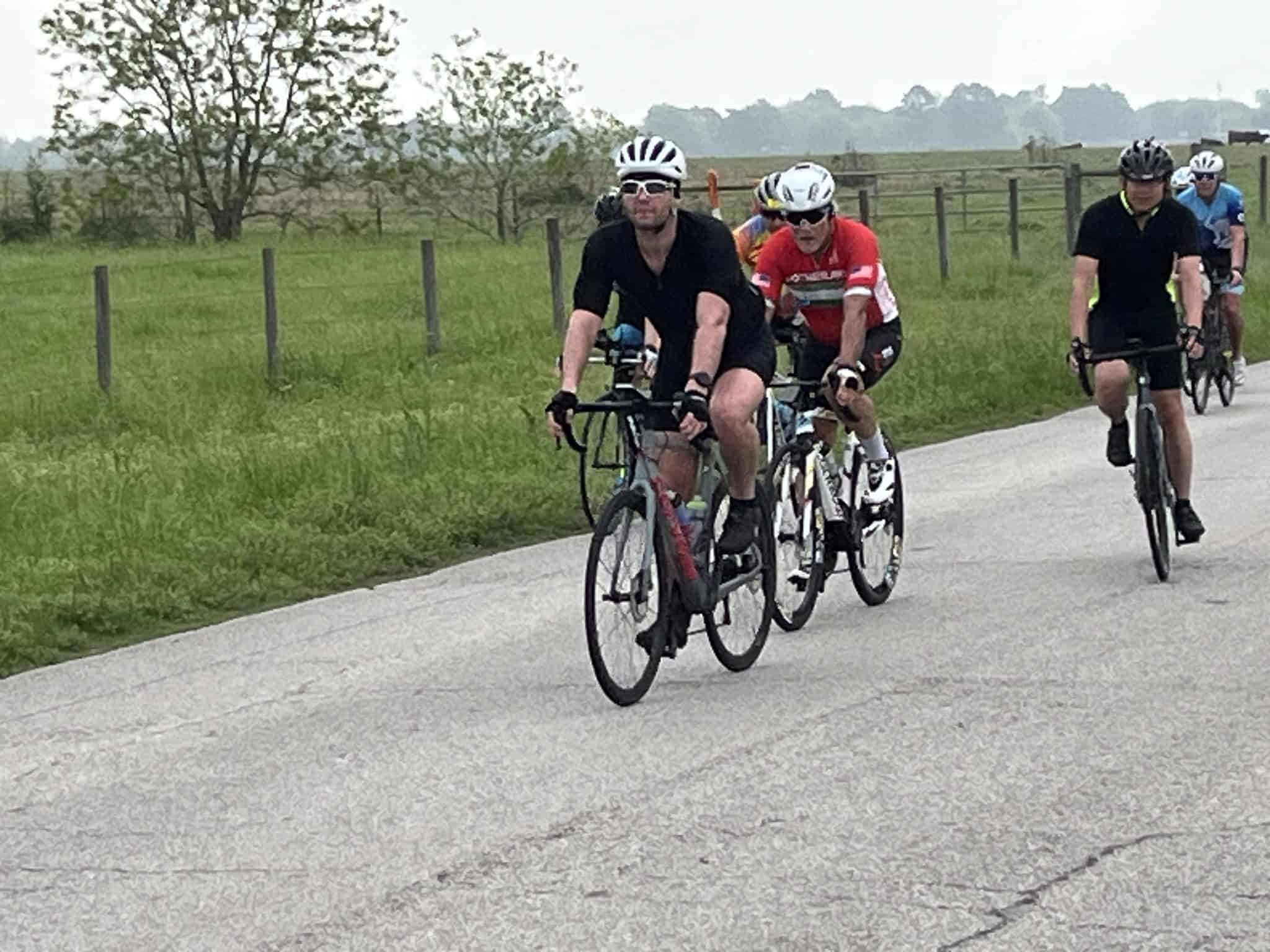 Brightly colored cyclists riding on a scenic rural road in the Bluebonnet Express event.
