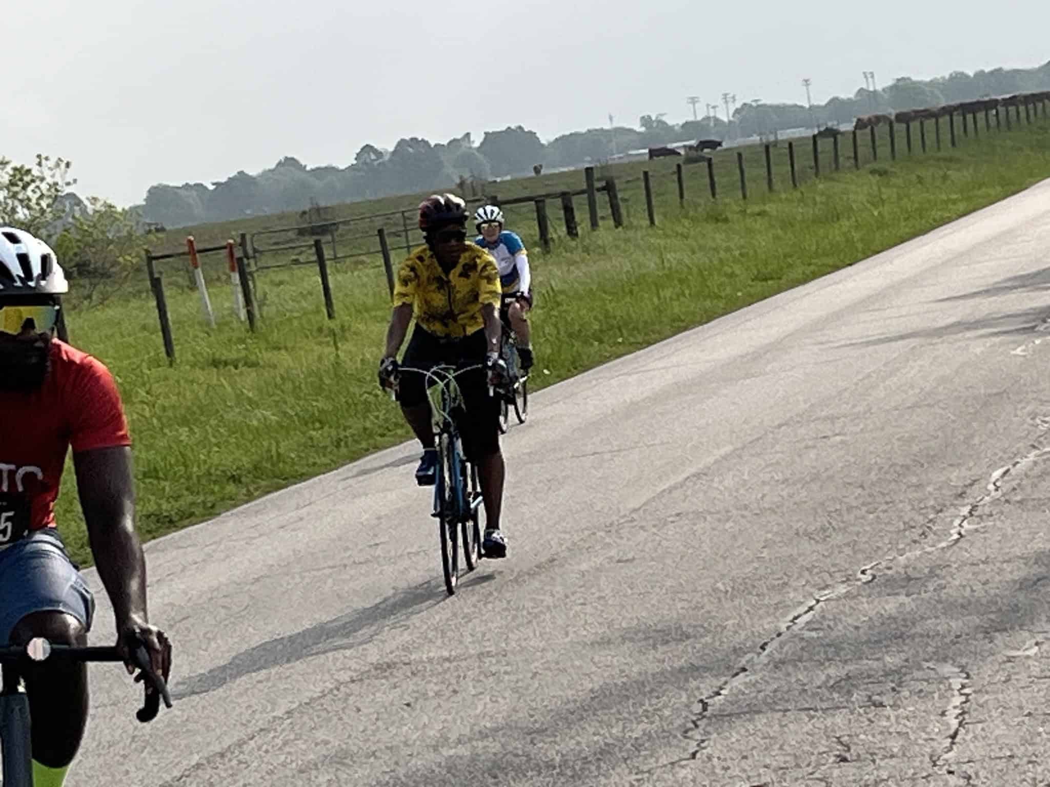 Cyclists riding on scenic rural roads with lush greenery and open sky, promoting outdoor biking adventures and cycling tours.